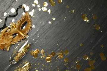 Beautiful golden carnival mask, glasses and confetti on gray textured table, flat lay. Space for...