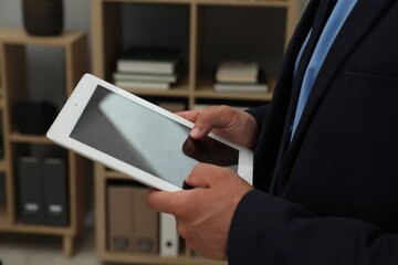 Businessman using tablet in office, closeup. Modern technology