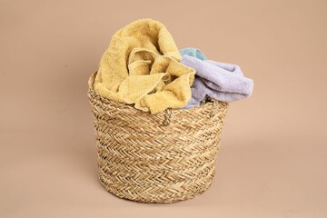 Wicker basket full of laundry on beige background