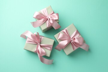 Gift boxes with bows on turquoise background, flat lay