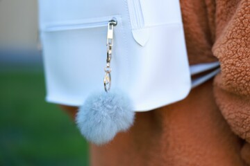Woman with faux fur keychain on her backpack outdoors, closeup. Selective focus