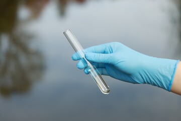 Examination of water quality. Researcher holding test tube with sample outdoors, closeup