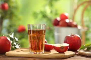 Tasty apple juice in glass and fresh fruits on wooden table outdoors