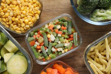 Different frozen vegetables on wooden table, flat lay
