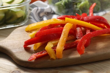 Slices of frozen bell peppers on wooden table, closeup