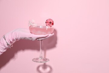 Woman holding glass of drink on pink background, closeup. Space for text