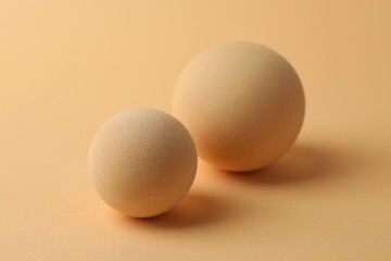 Two textured balls on beige background, closeup