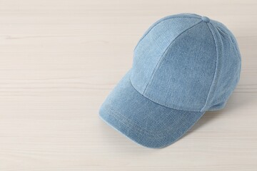 Stylish denim baseball cap on wooden table. Mockup for design