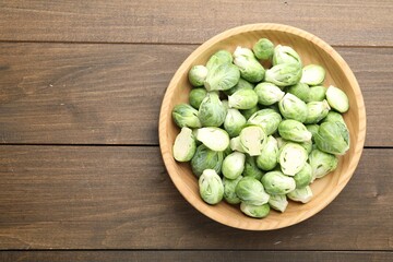 Fresh green Brussels sprouts in bowl on wooden table, top view. Space for text