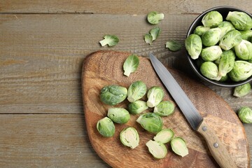 Fresh Brussels sprouts, board and knife on wooden table, flat lay. Space for text