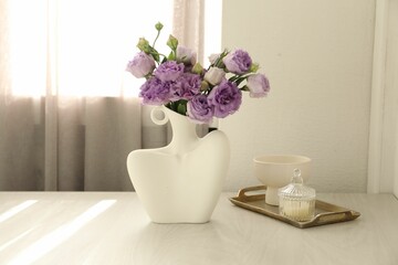 Stylish vase with beautiful flowers and decor on white wooden table at home