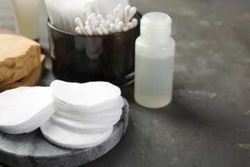 Many cotton pads and other toiletries on grey textured table, closeup