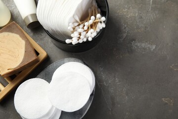 Many cotton pads and swabs on grey textured table, flat lay. Space for text