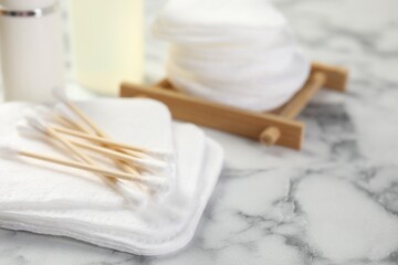 Cotton pads and swabs on light marble table, closeup