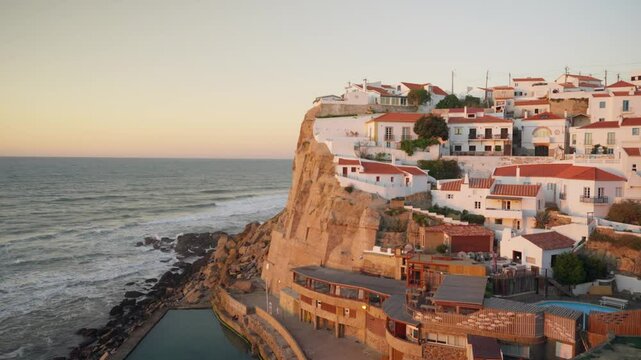 Small picturesque village or town of Azenhas do mar in Portugal coast at sunset. Sun setting over the small white houses on a cliff overlooking the ocean. Touristic town with amazing view to sea