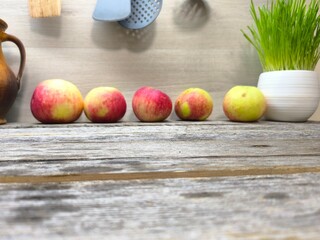 Beautiful juicy apples are lying on a table along the wall