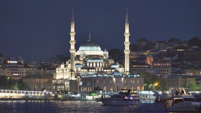 New Mosque (Yeni Cami) mirrored in Bosfor Golden Horn estuary at night, Istanbul Turkey