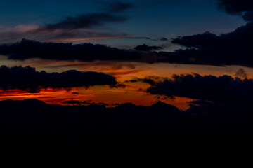 Obraz premium Sunset in the Alps. Mountain silhouettes in the red sunset light and burning sky on the background