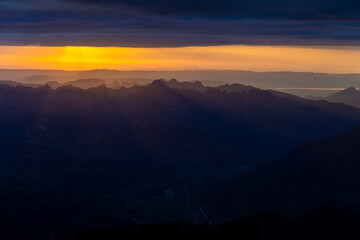 Sunset burning red and orange sky above the snow summits and rocky peaks of the Alps. Beautiful mountain sunset and sunrise in Chamonix valley on the ascent to Montblanc