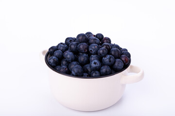 Small ceramic pot filled with fresh blueberries on a clean white background, showcasing the fruit in a simple and minimalist stock photo