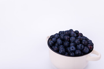 Minimalist photo of a ceramic pot full of blueberries placed on a white background, highlighting the simplicity and freshness of the fruit