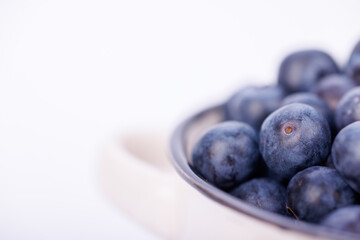 Ceramic bowl filled with juicy blueberries in a crisp, detailed view on an infinite white background