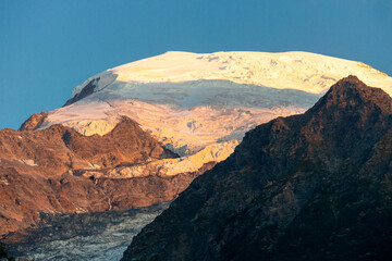 Fototapeta premium Sunset burning red and orange sky above the snow summits and rocky peaks of the Alps. Beautiful mountain sunset and sunrise in Chamonix valley on the ascent to Montblanc