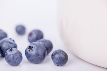 Ceramic bowl full of blueberries in a sharp close-up against a pure white infinite background