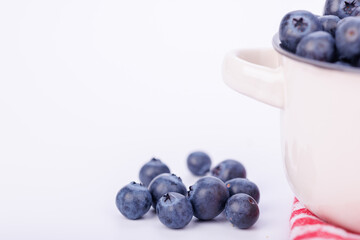 Close-up of a ceramic pot brimming with blueberries on a pure white infinite background