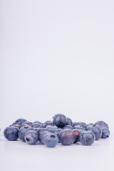 Detailed view of a heap of fresh blueberries on a pure white background, emphasizing their texture and vibrant color in a beautiful arrangement
