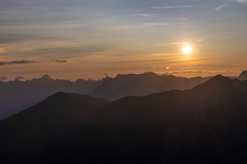 Sunset burning red and orange sky above the snow summits and rocky peaks of the Alps. Beautiful mountain sunset and sunrise in Chamonix valley on the ascent to Montblanc