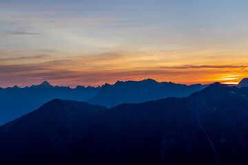 Sunset burning red and orange sky above the snow summits and rocky peaks of the Alps. Beautiful mountain sunset and sunrise in Chamonix valley on the ascent to Montblanc