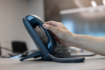 close up man hand touching telephone for call  or connecting with partner,vendor or customer at computer desktop operation room, hotline and helpline concept