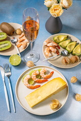 Romantic dinner setting featuring cheese, shrimp, kiwi, avocado, and rose wine