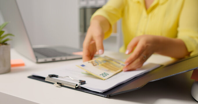 Woman opening the clipboard and raising a pile of money. Accountant taking money out of a clipboard.