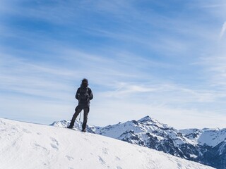 Snowshoer standing on snowy ridge in mountain landscape