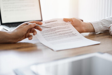 Naklejka premium Businesswoman lawyer pointing into contract special points admitting something for colleague or client at the wooden desk in office. Business people teamwork and partnership, meeting concept