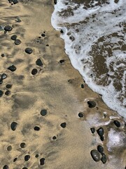 Sea water foam on the shore with sand and pebbles. Abstract seascape background wallpaper with copy space
