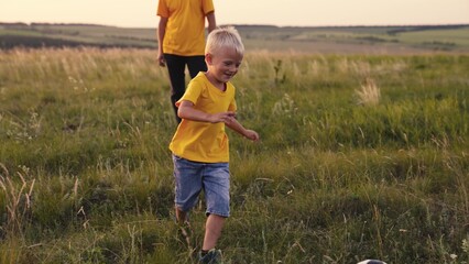 happy family sunset. group people playing soccer with soccer ball. boys play football with their father. child kid run around field kick ball with their foot. children play green field with brothers