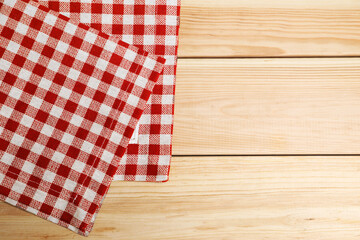 Obraz premium Folded tablecloth with checkered pattern on light wooden table, top view. Space for text