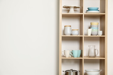 Wooden shelving unit with kitchenware on white background, space for text