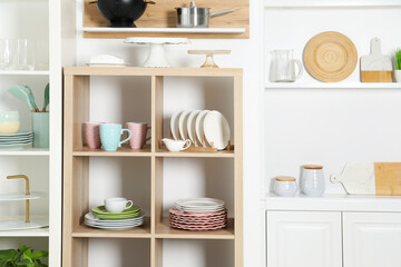 Shelving units with kitchenware near white wall indoors