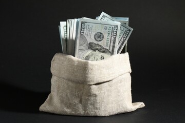 Dollar banknotes in burlap sack on dark background