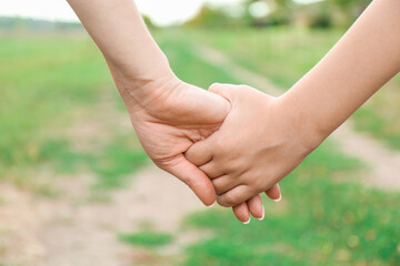 Mother and son holding hands outdoors, closeup
