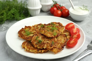 Delicious potato pancakes with fresh tomatoes served on grey table