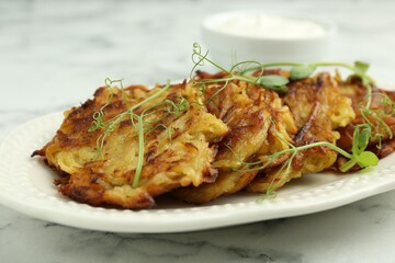 Delicious potato pancakes with fresh microgreens on white marble table, closeup