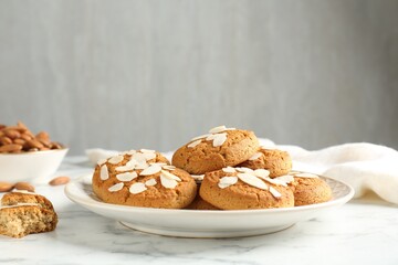 Tasty cookies with almond flakes on white marble table, closeup