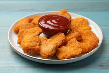 Delicious chicken nuggets with ketchup on blue wooden table, closeup