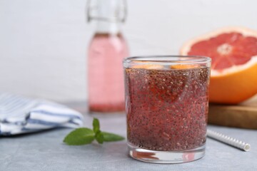 Glass of drink with chia seeds and grapefruit on grey table, closeup