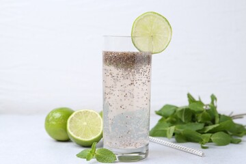 Glass of drink with chia seeds and lime on white table, closeup